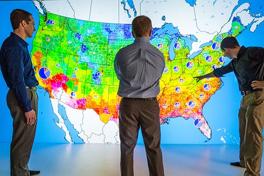 Three men stand in front of a colorful.