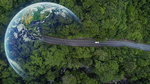 Aerial image of a car driving on pavement through a heavily wooded area toward the planet Earth faded on the left.