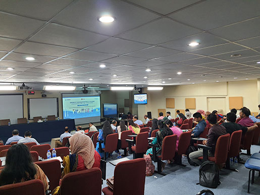 Group of people sit and watch presentation on Energy Fundamentals for Bangladesh Energy Sector Workforce.