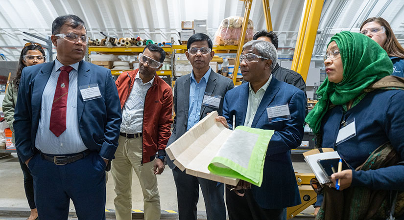 Tour group looks at wind turbine component materials inside lab.