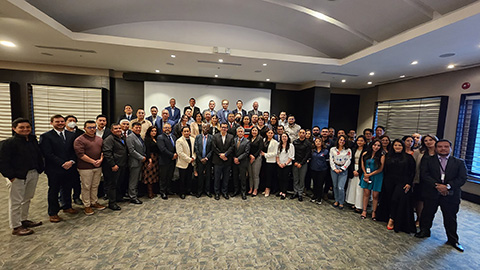 A formal group picture of at least thirty people in a conference room.