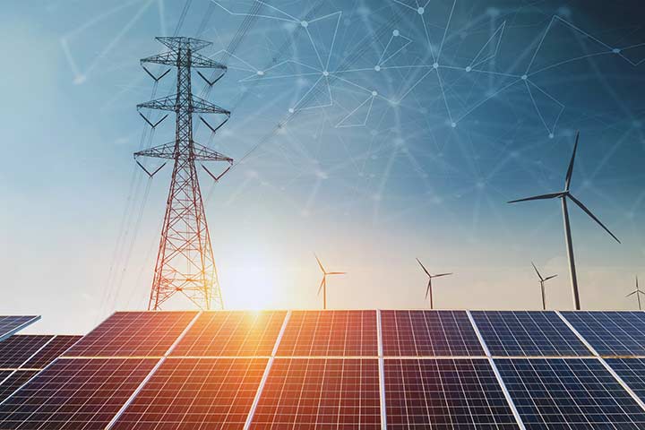 A stock image of transmission pylons, wind turbines, and solar panels, with an digitally overlaid network in the sky. 