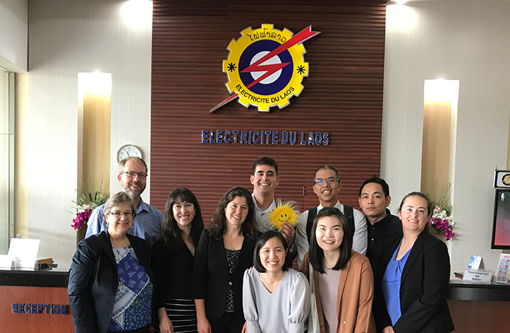 A group of people smiling for a photo in front of a desk.