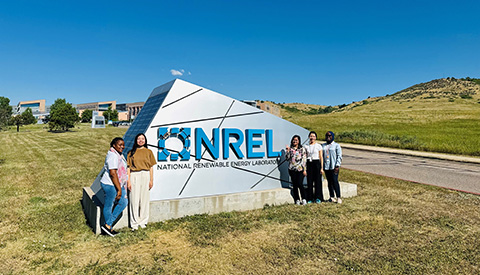 Women in Power System Transformation interns pose in front of the NREL entrance sign at the South Table Mountain Campus.