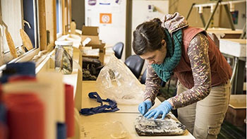 Person bends over work table to fix marine energy components