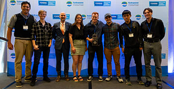 Team members pose for photo while holding prize