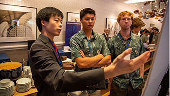 Three students point and look at poster