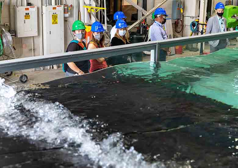 People stand next to a wave tank