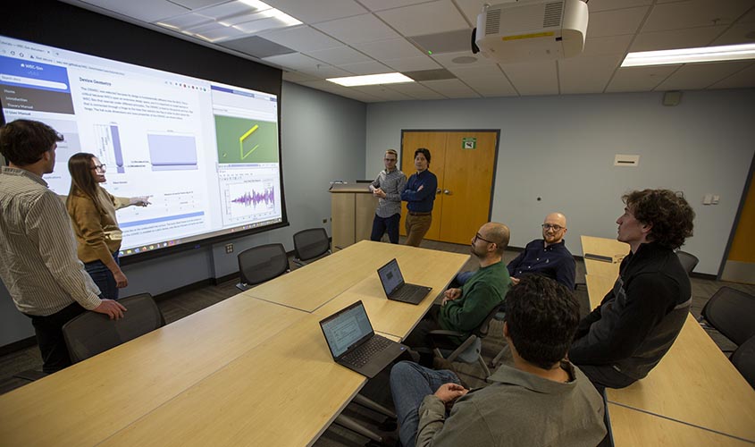 A room of researchers considering a projected screen.