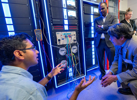 A group of people gather around a power grid.
